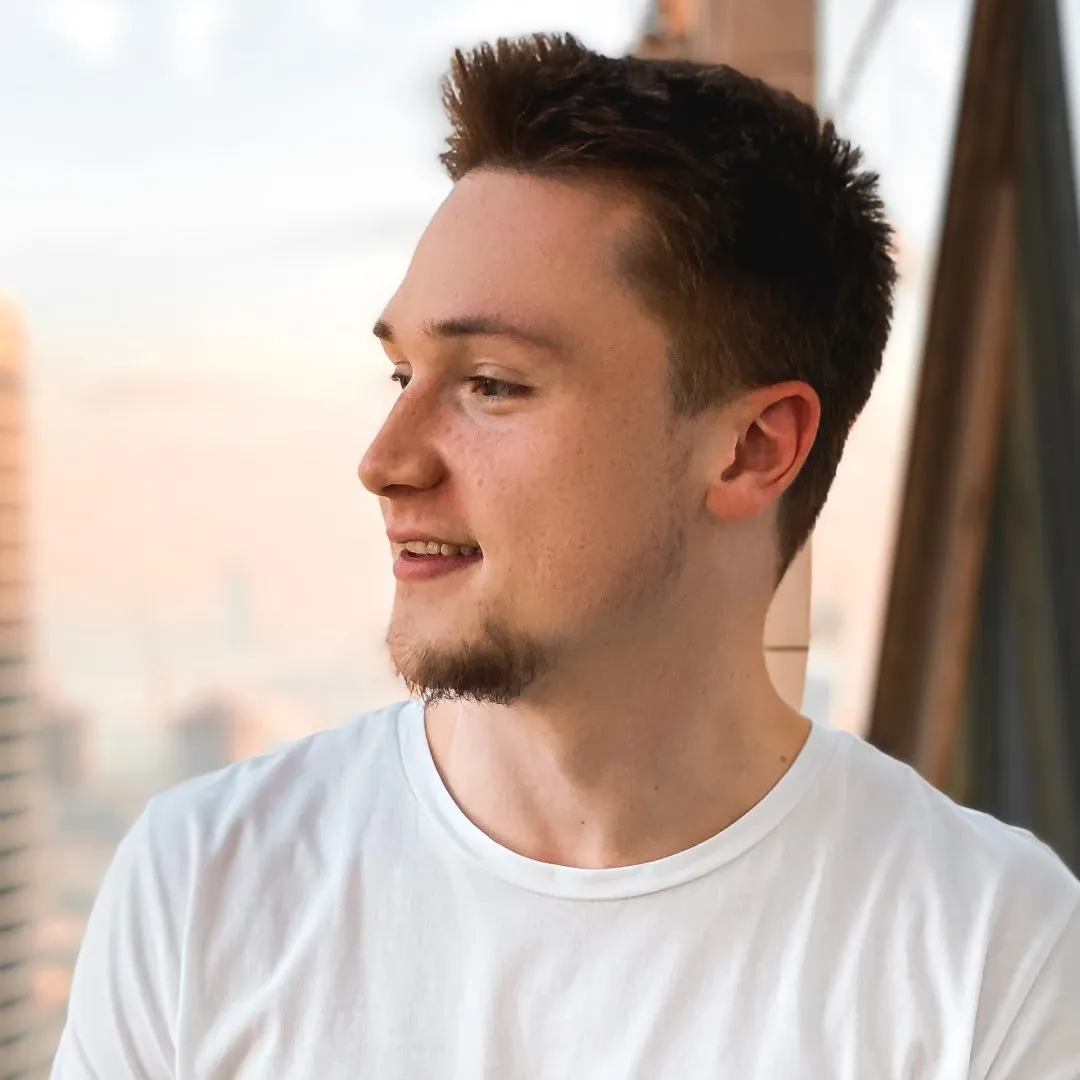 A man in a white t - shirt looks off into the distance.